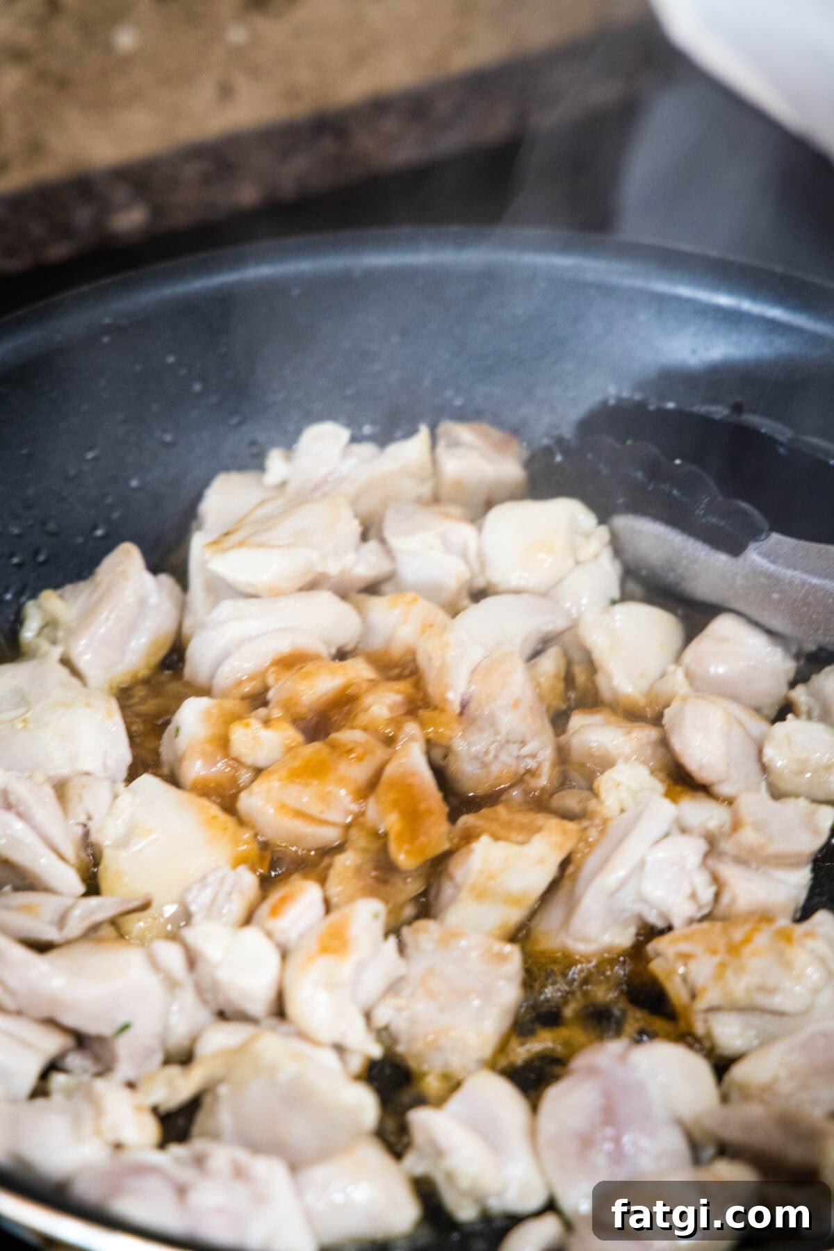 Crispy Honey Sriracha Chicken Bites 4 adding honey sriracha sauce to skillet with chicken