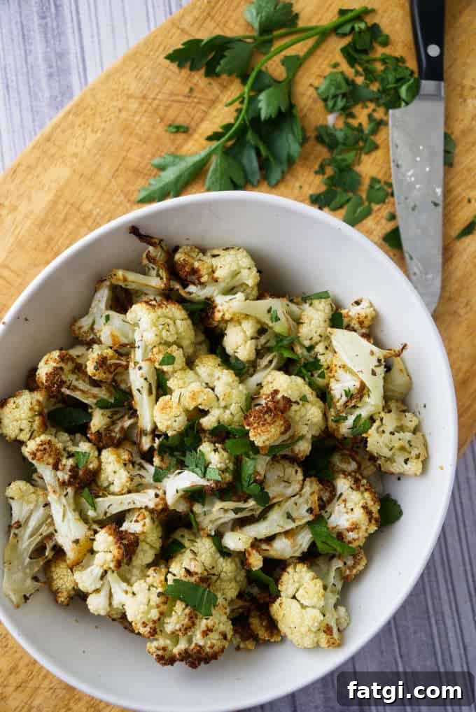 Cauliflower in a bowl with parsley on a cutting board.