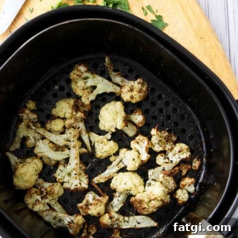 Roasted cauliflower in an air fryer basket.
