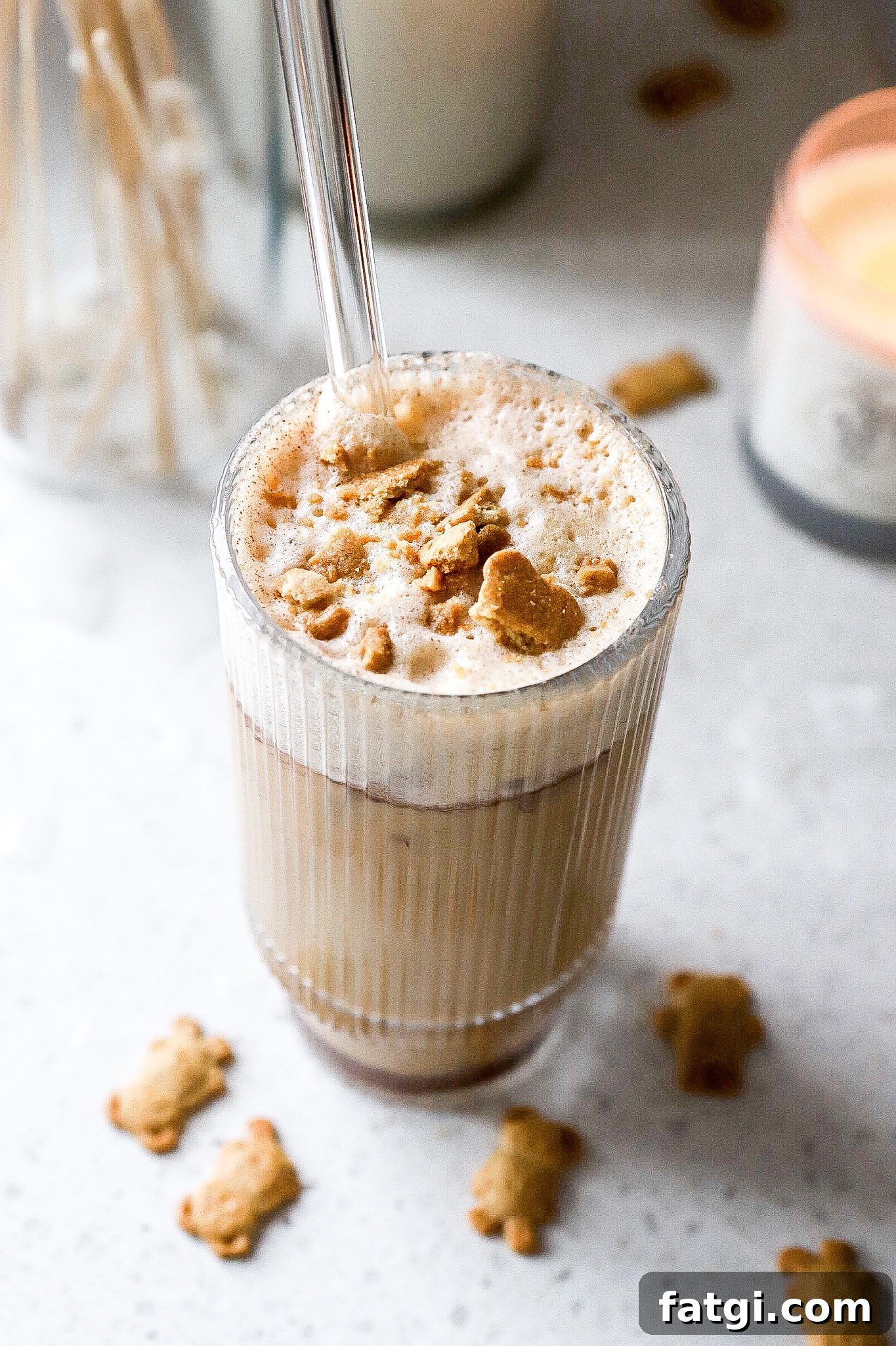 Side angle of espresso teddy graham latte recipe in glass with crushed teddy grahams on top.