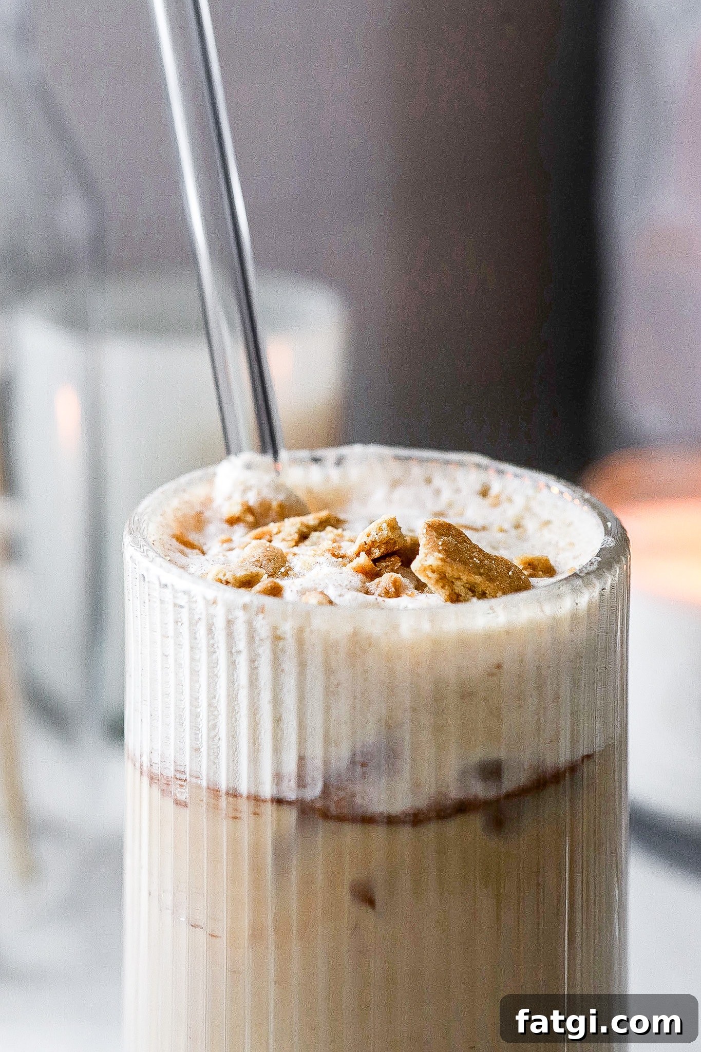 Close up view of a nostalgic iced teddy graham latte with glass straw coming out of the glass.