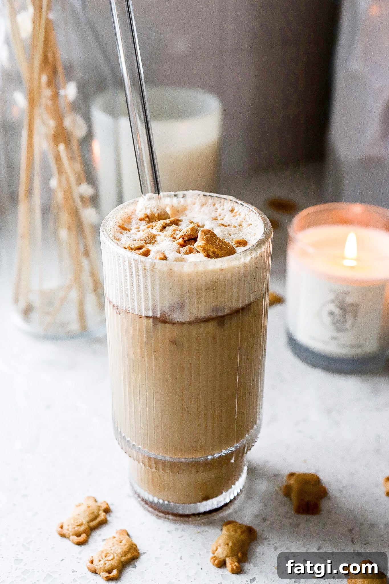 Side view of viral teddy graham latte with crushed teddy grahams on top and candles in background.
