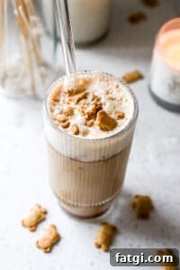 Side angle of espresso teddy graham latte recipe in glass with crushed teddy grahams on top.