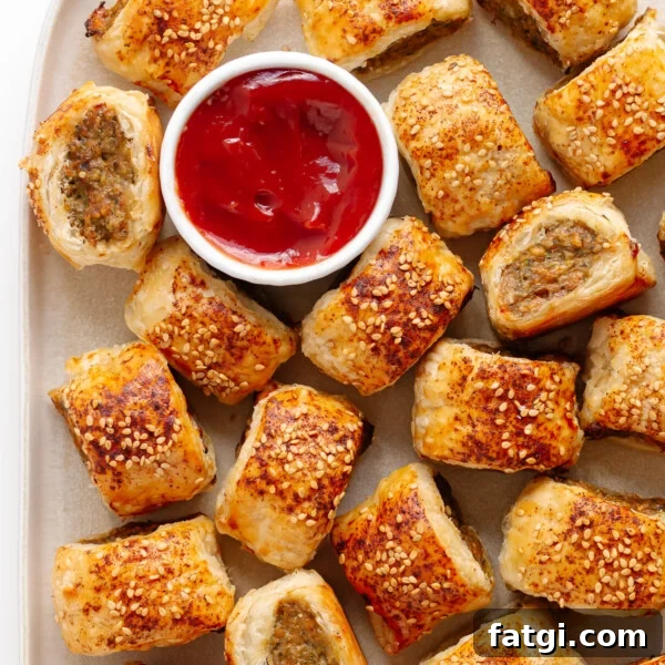 Closeup of chicken sausage rolls on a platter with small bowl of ketchup.