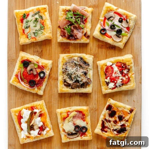 Nine small puff pastry pizzas with different toppings on a wood board.