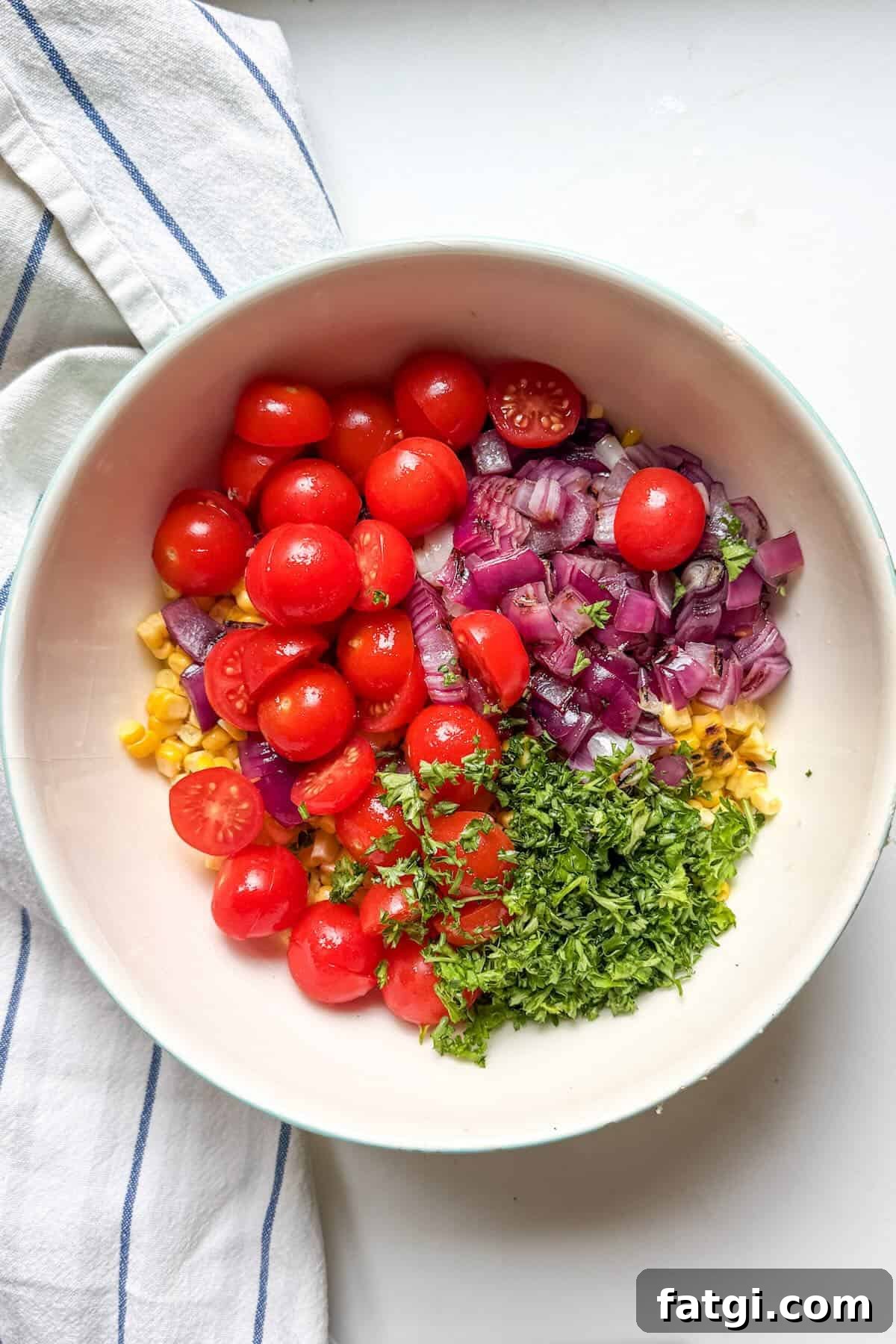 Charred corn, sliced cherry tomatoes, grilled onions and fresh parsley in a bowl.