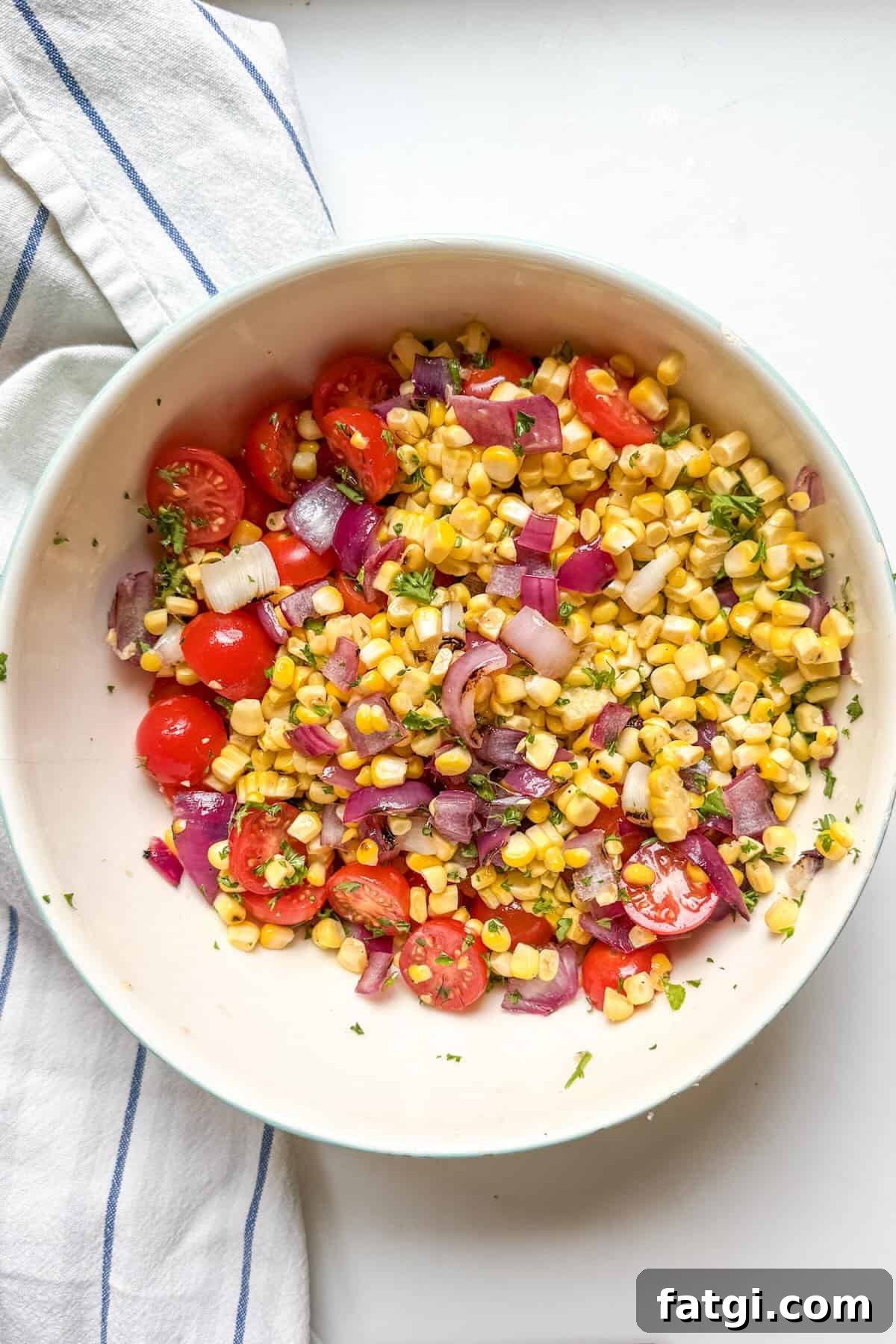Tossed grilled corn salad with, tomatoes, and lime dressing in a large bowl.