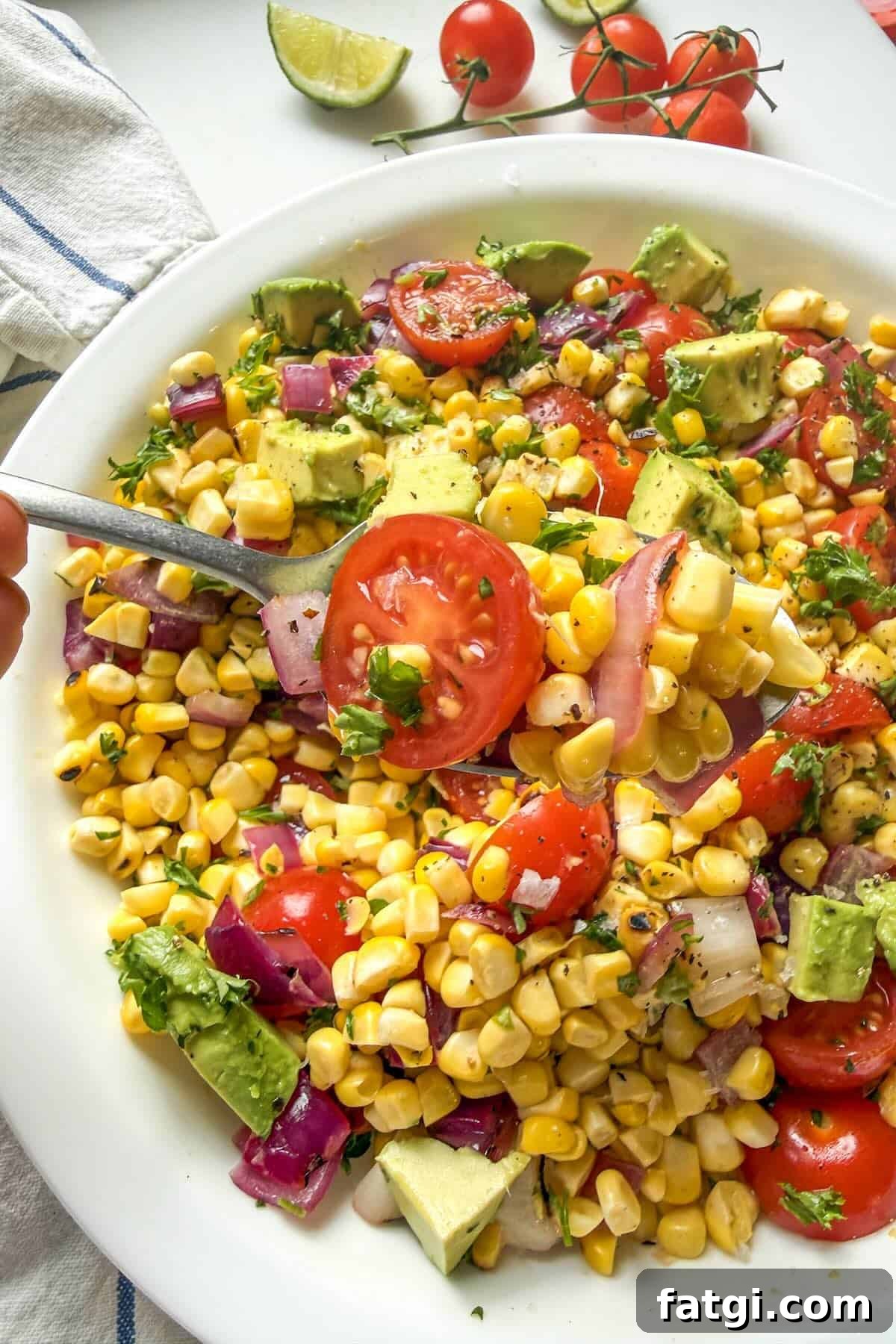 Serving spoon scooping grilled corn salad with avocado and charred corn.