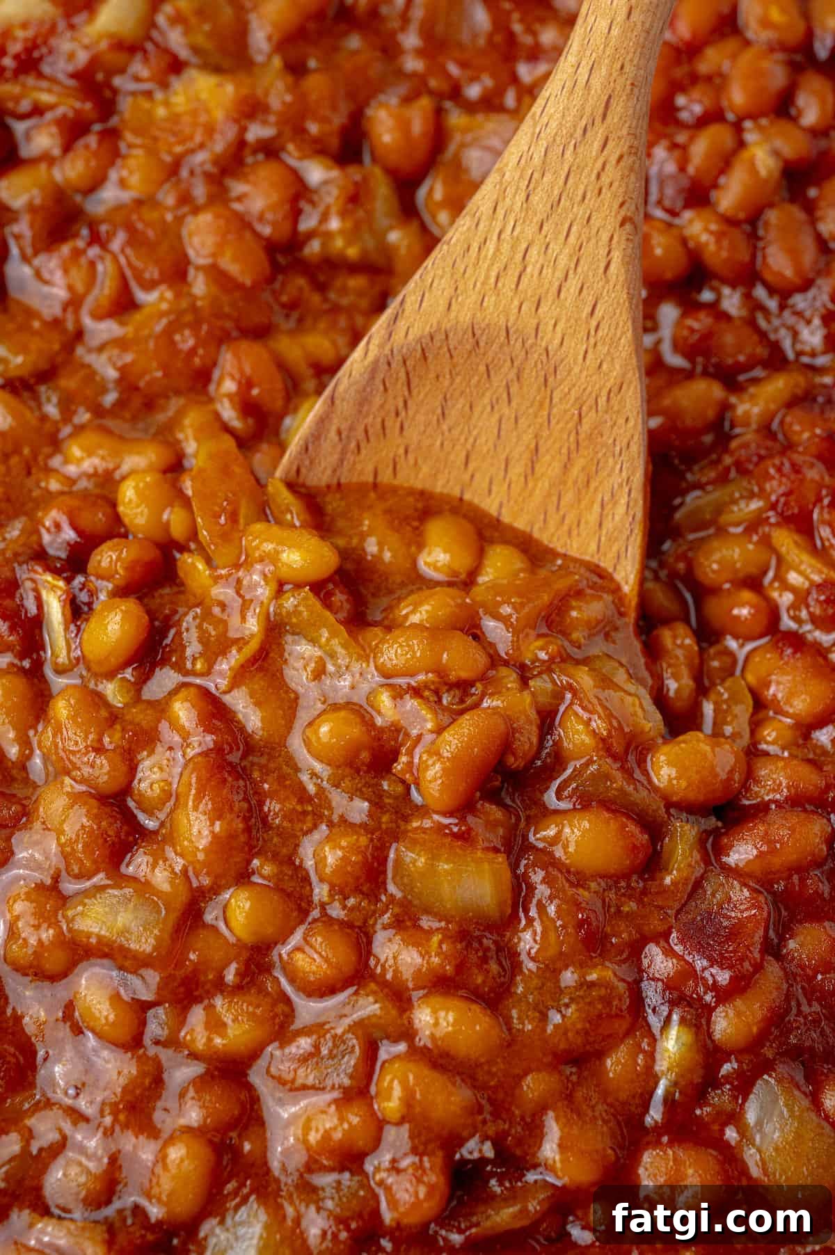 Baked pork and beans with a wooden spoon.