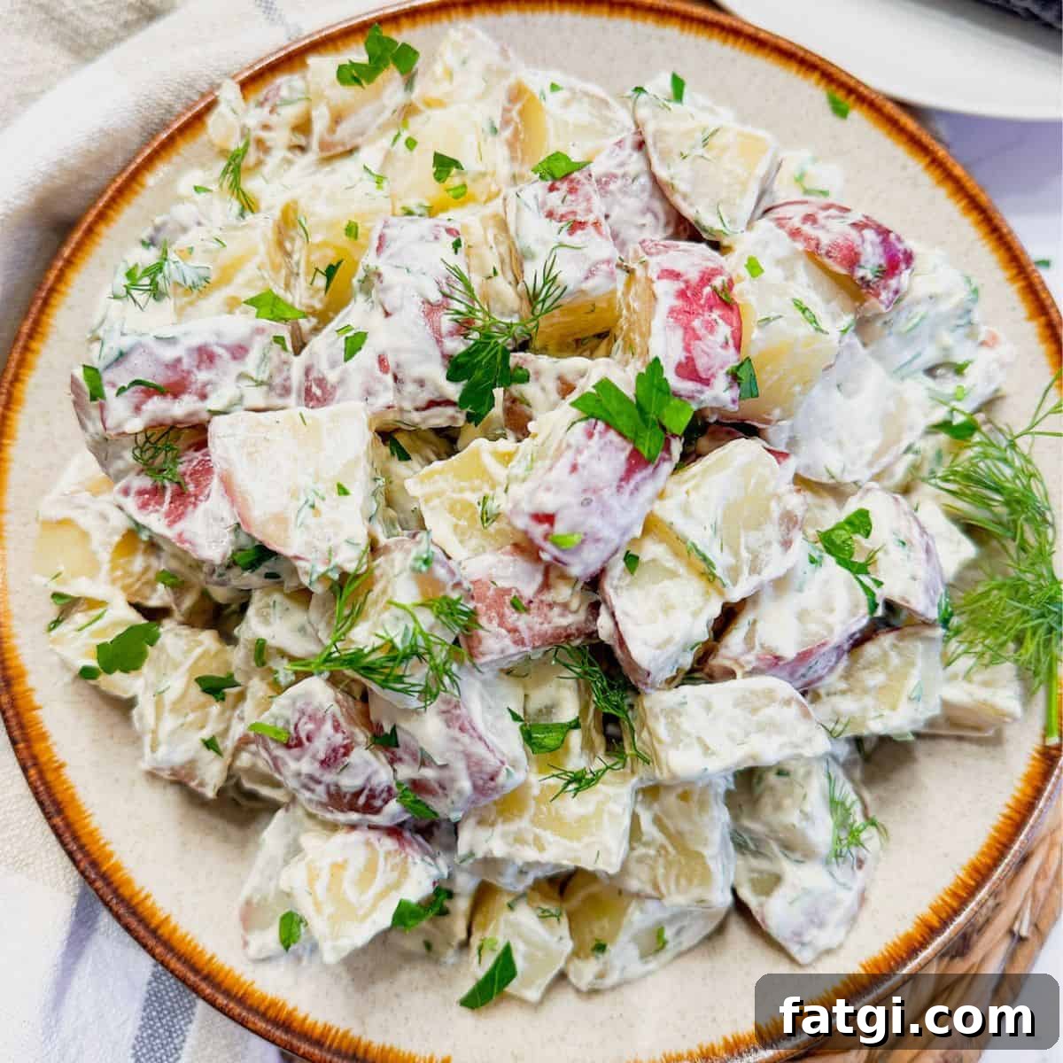 A plate of red potato salad topped with fresh dill.