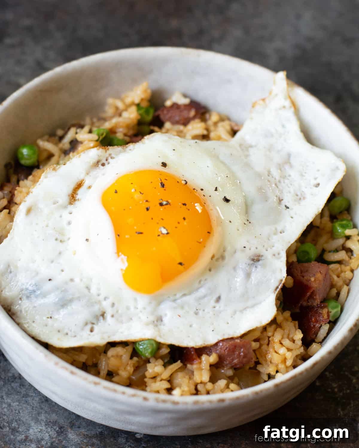 A bowl of breakfast fried rice with a sunny side up fried egg on top.