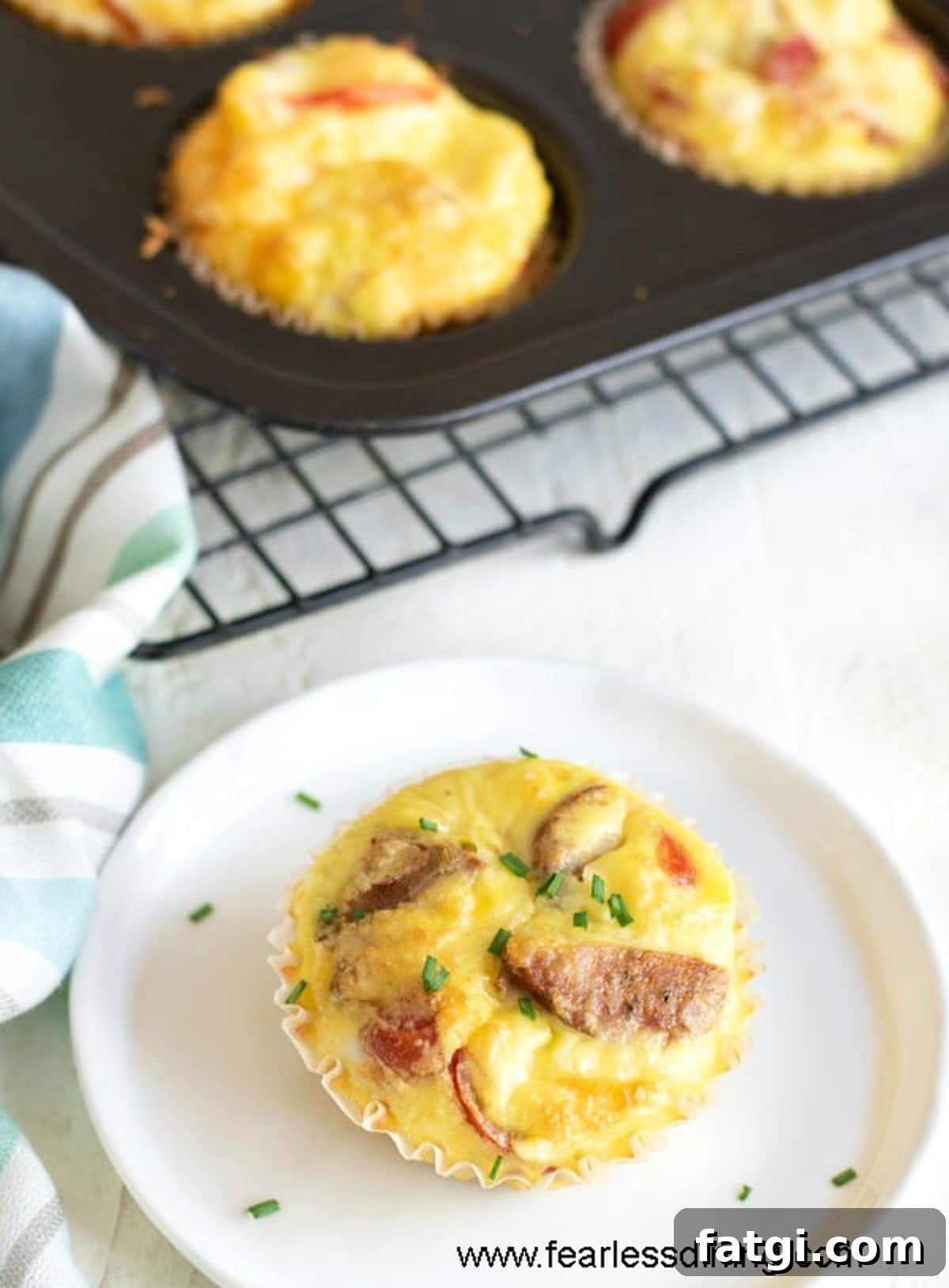 A sausage stuffed egg muffin cup on a white plate.