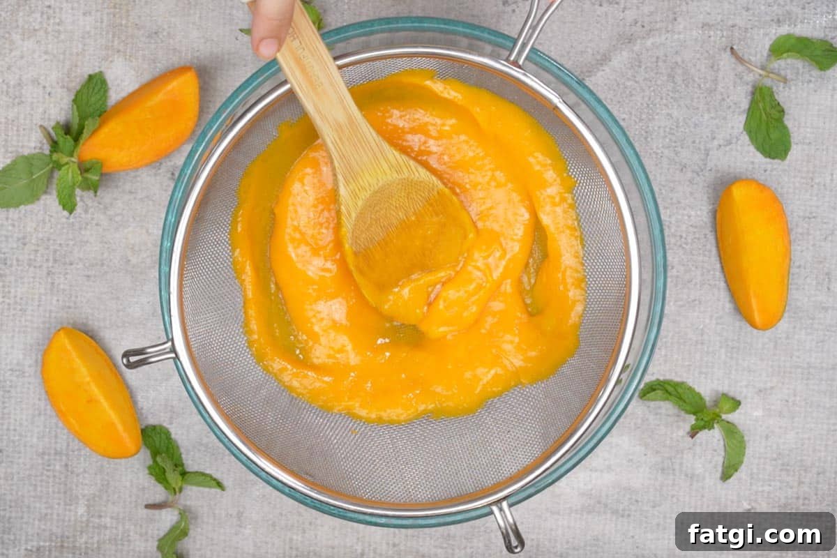 Mango pulp passing through a strainer.