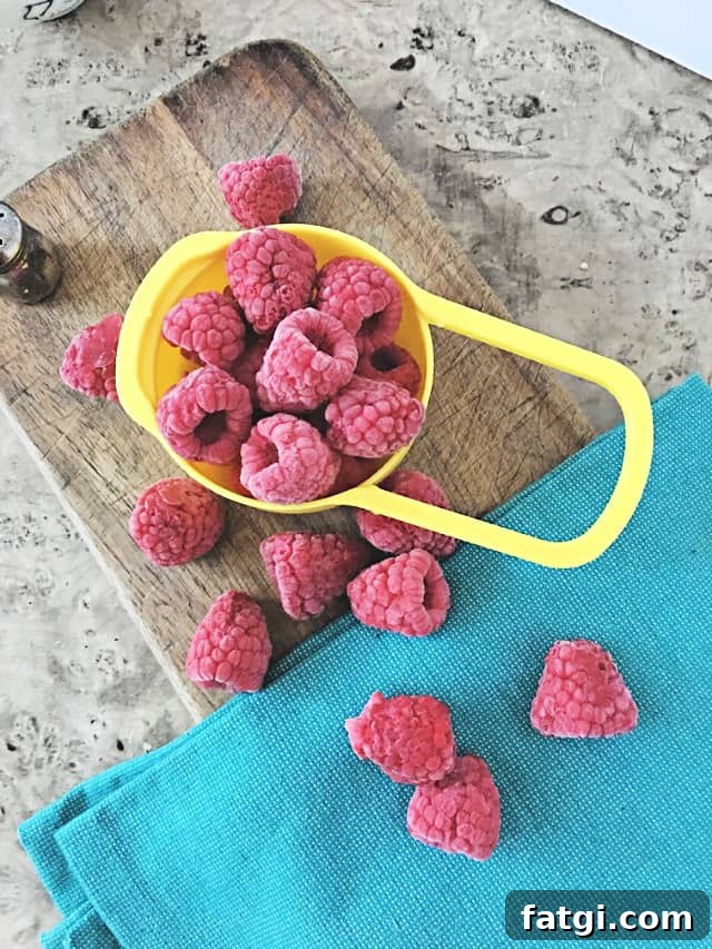 How to Freeze Raspberries for Fresh Flavor All Year 2 cup holding frozen raspberries on wooden background