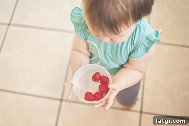 How to Freeze Raspberries for Fresh Flavor All Year 6 Small child holding a plastic container of raspberries