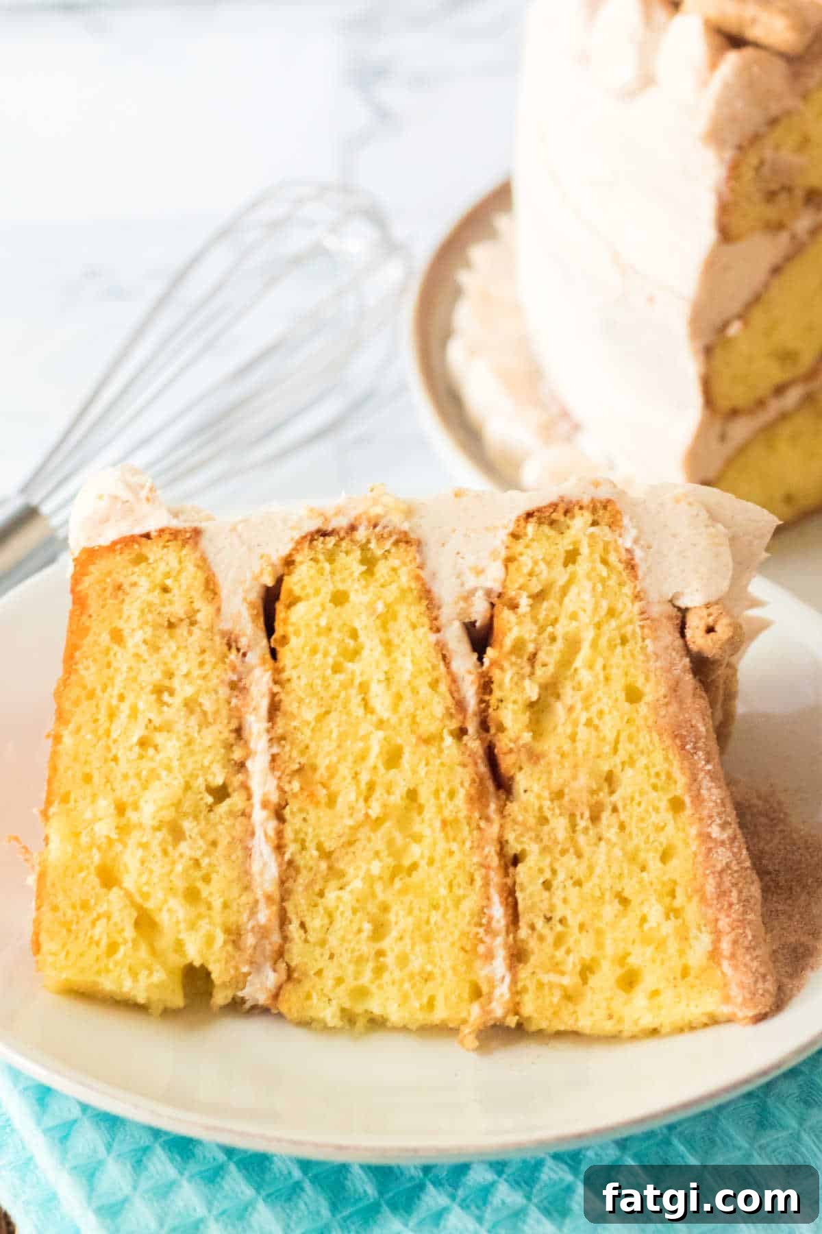 A slice of three layer cake on a white plate on a blue napkin.