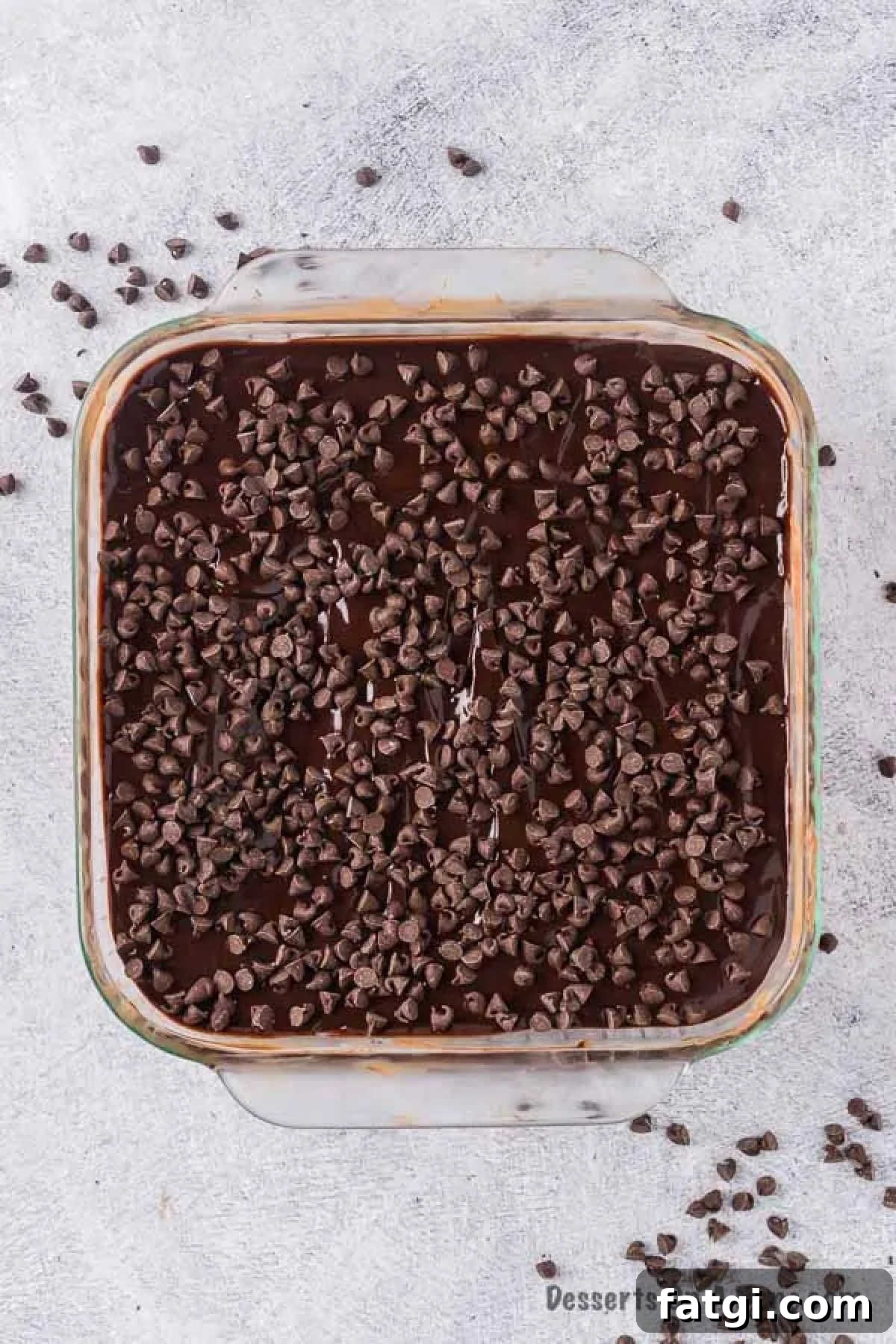Ganache poured on cake and chocolate chips sprinkled on top. 