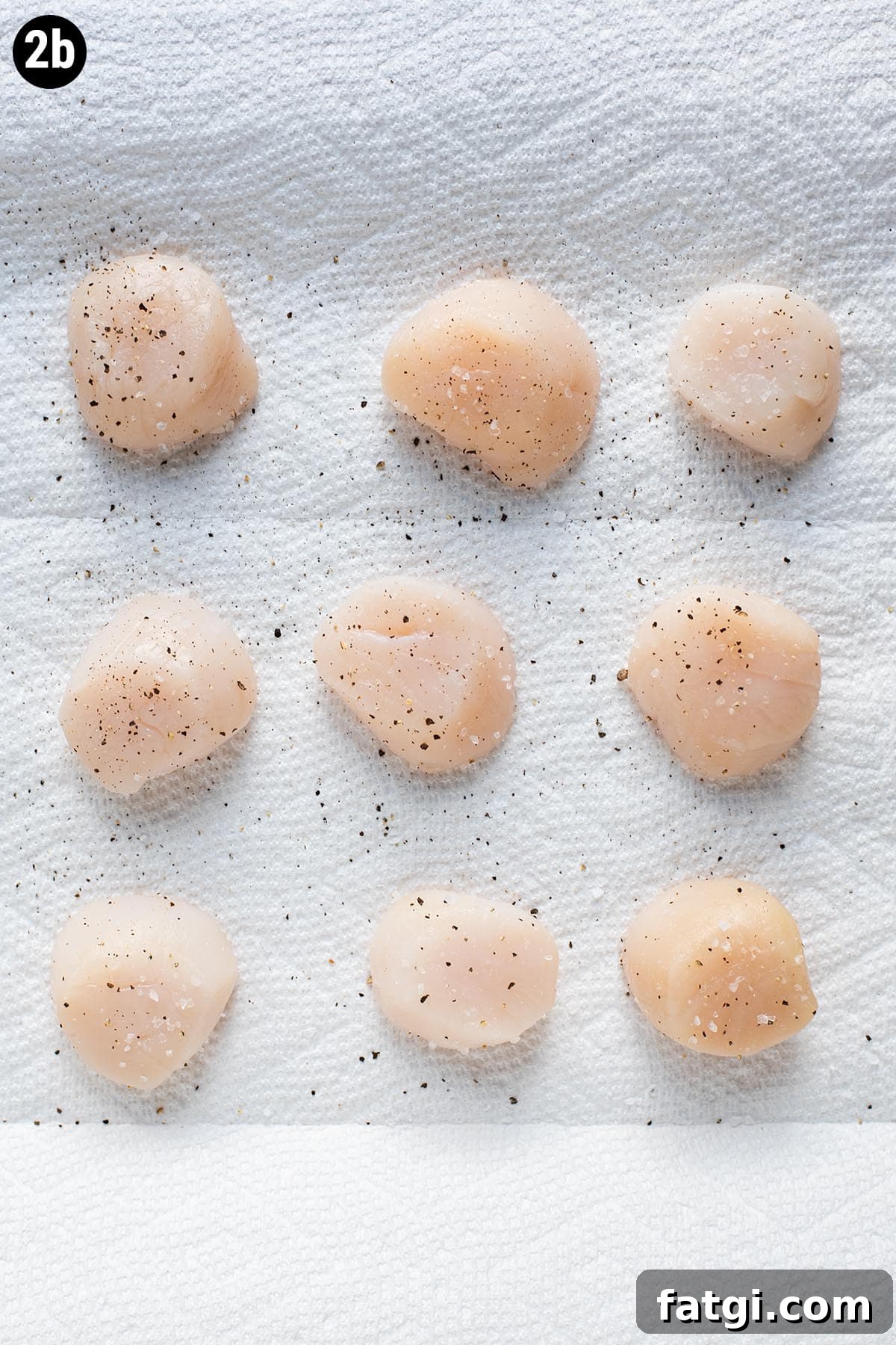 Sweet and Smoky Bacon Wrapped Scallops Recipe 5 Seasoned raw sea scallops with salt and pepper on a sheet of paper towel.