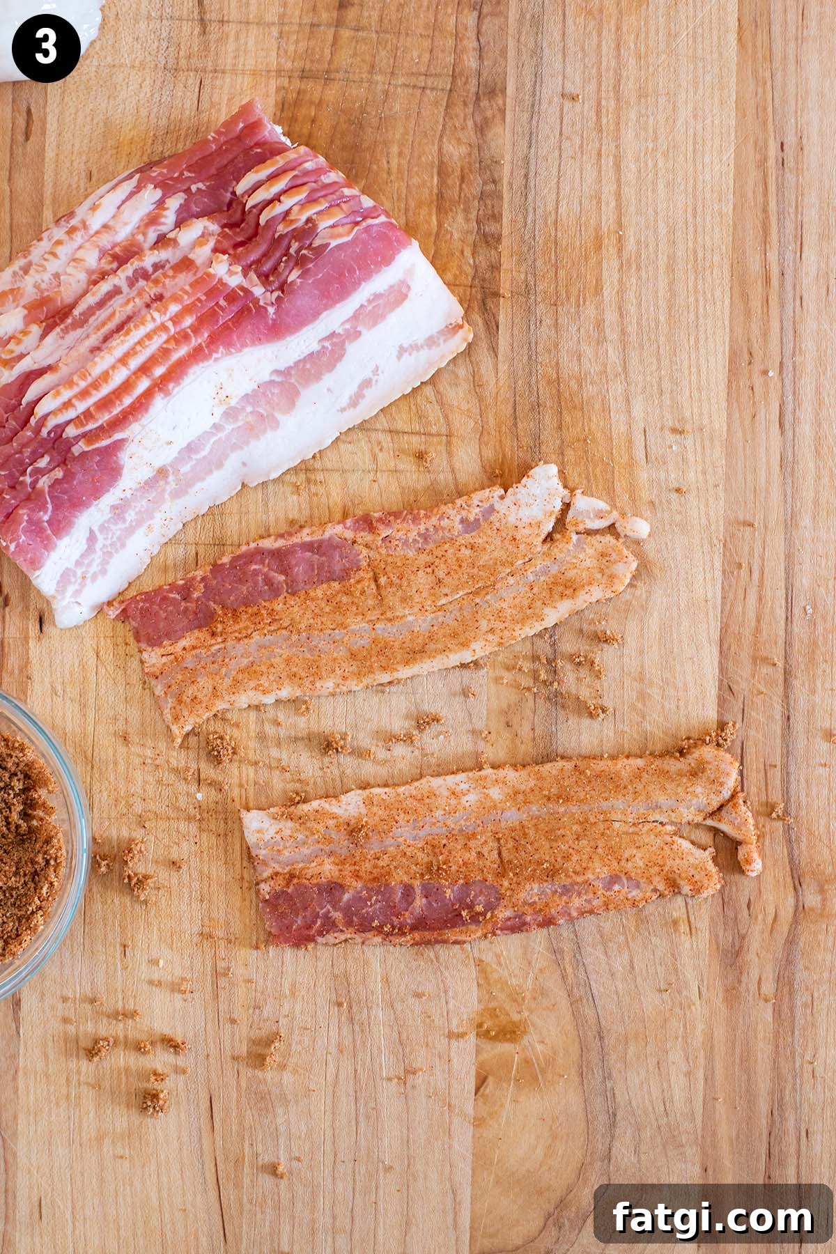 Sweet and Smoky Bacon Wrapped Scallops Recipe 6 Half slices of raw bacon rubbed with brown sugar and paprika on a wooden cutting board.
