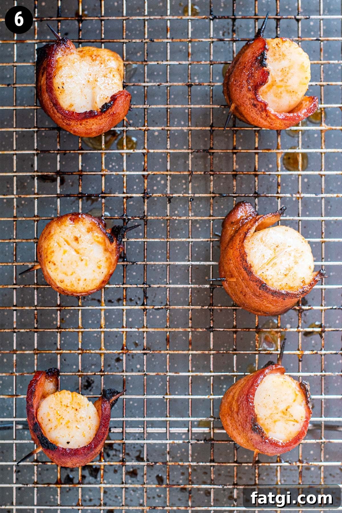 Sweet and Smoky Bacon Wrapped Scallops Recipe 9 Fully cooked golden brown scallops wrapped in bacon on a wire rack stacked on a baking sheet.