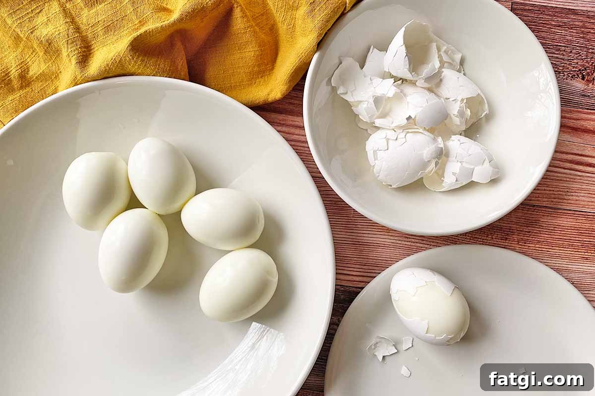 Horizontal image of peeling hard-boiled eggs, separated the skin in a different bowl.