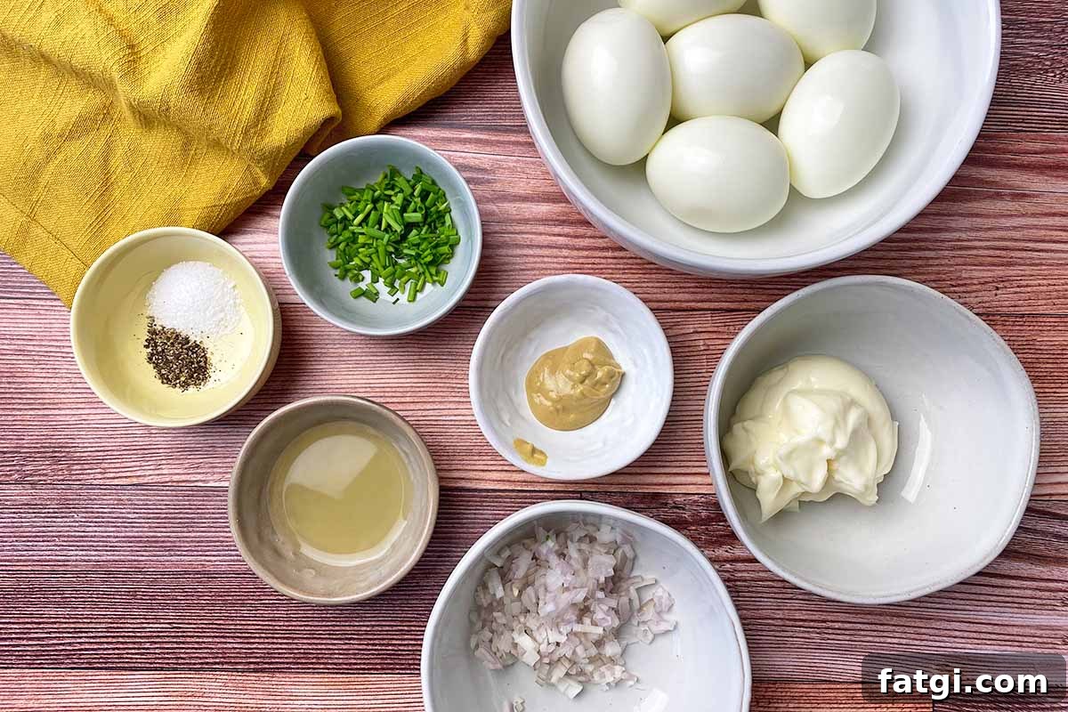 Horizontal image of measured and prepared ingredients in assorted bowls on a wooden surface next to a white towel.