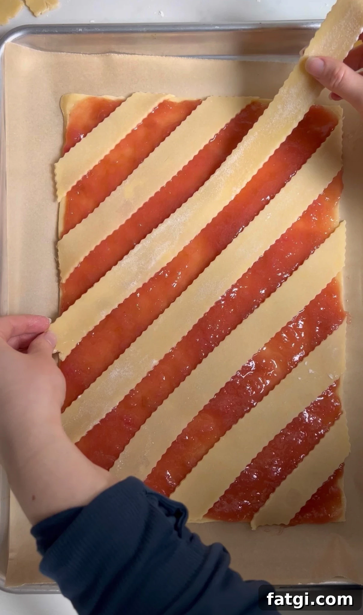 Adding strips of pastry dough to a rhubarb pastry to create a diagonal lattice.