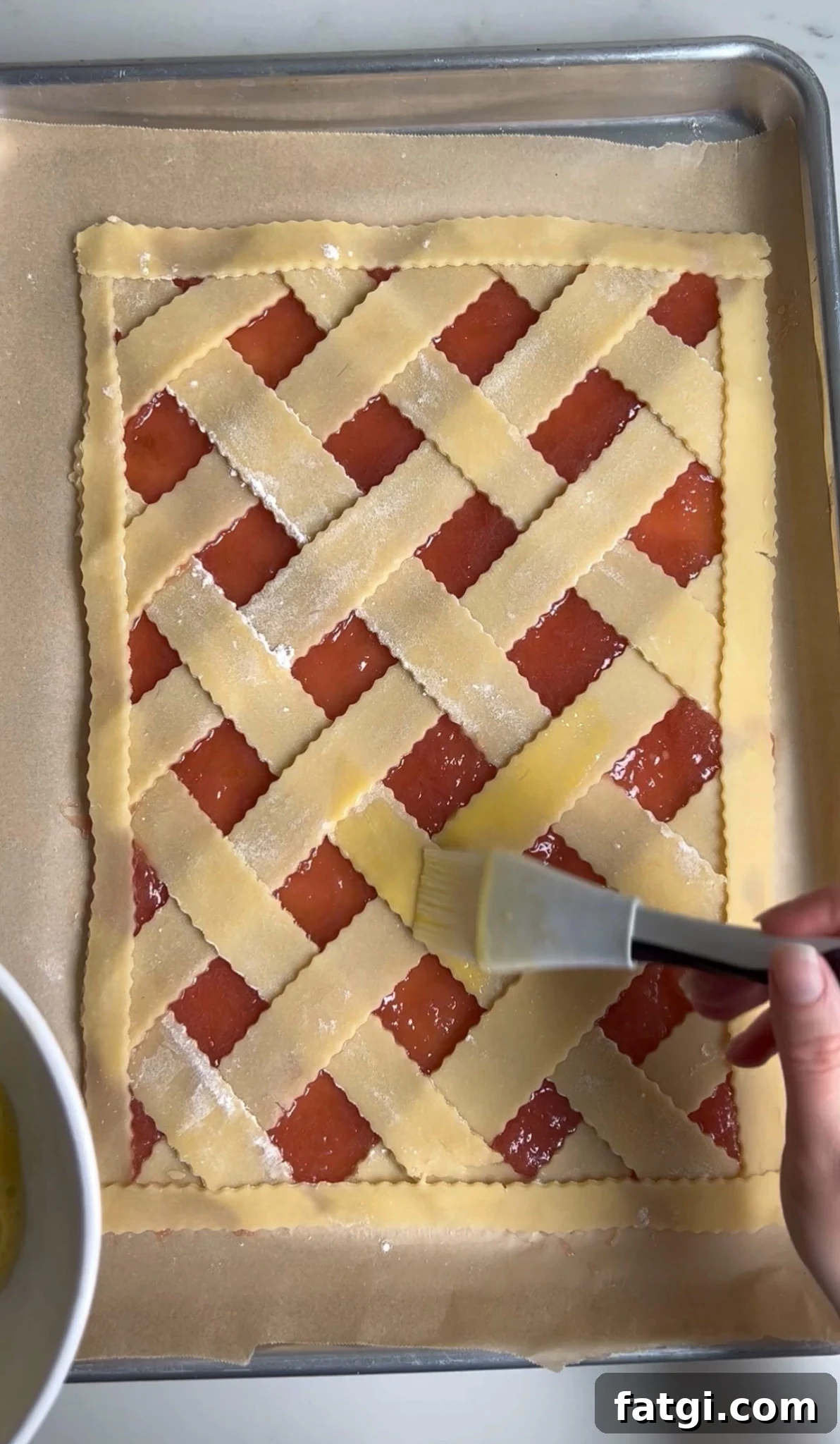 Adding egg wash to a pastry.