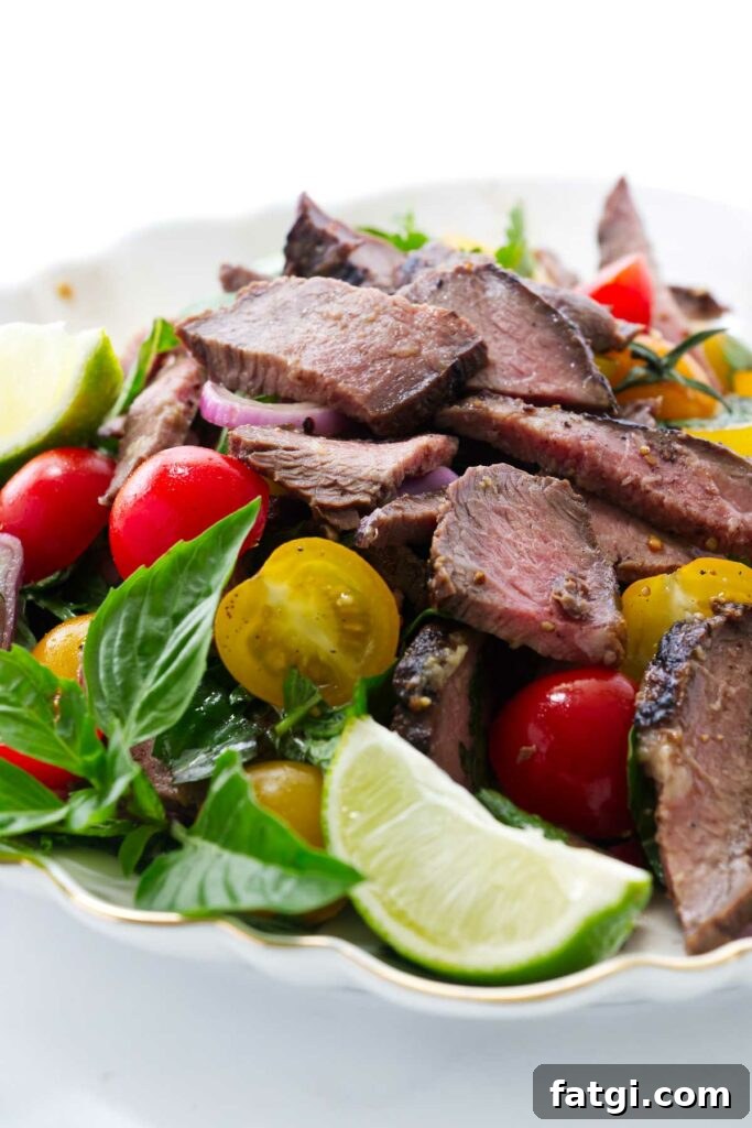 Slices of grilled steak in a salad plate with lime and tomatoes.