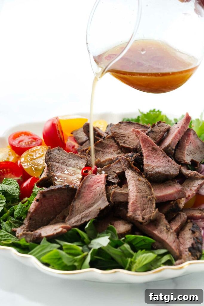 Pouring a chili lime dressing over a steak salad.