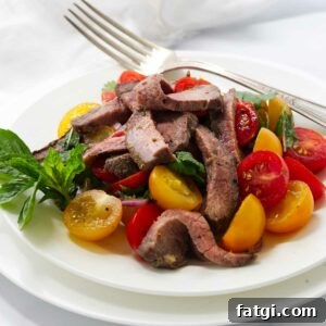A tomato and herb steak salad on a white plate.