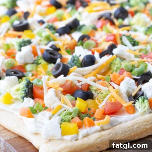 crescent roll veggie pizza on a wooden cutting board.
