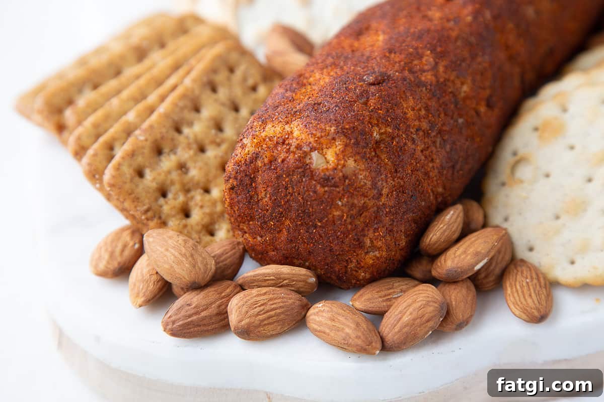 Homemade Cheese Log Recipe 9 cheese log coated in chili powder next to almonds and crackers.