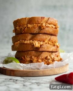3 sandwiches stacked on each other on small wooden board