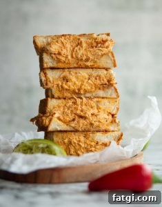 4 sandwich halves stacked on each other on small wooden board