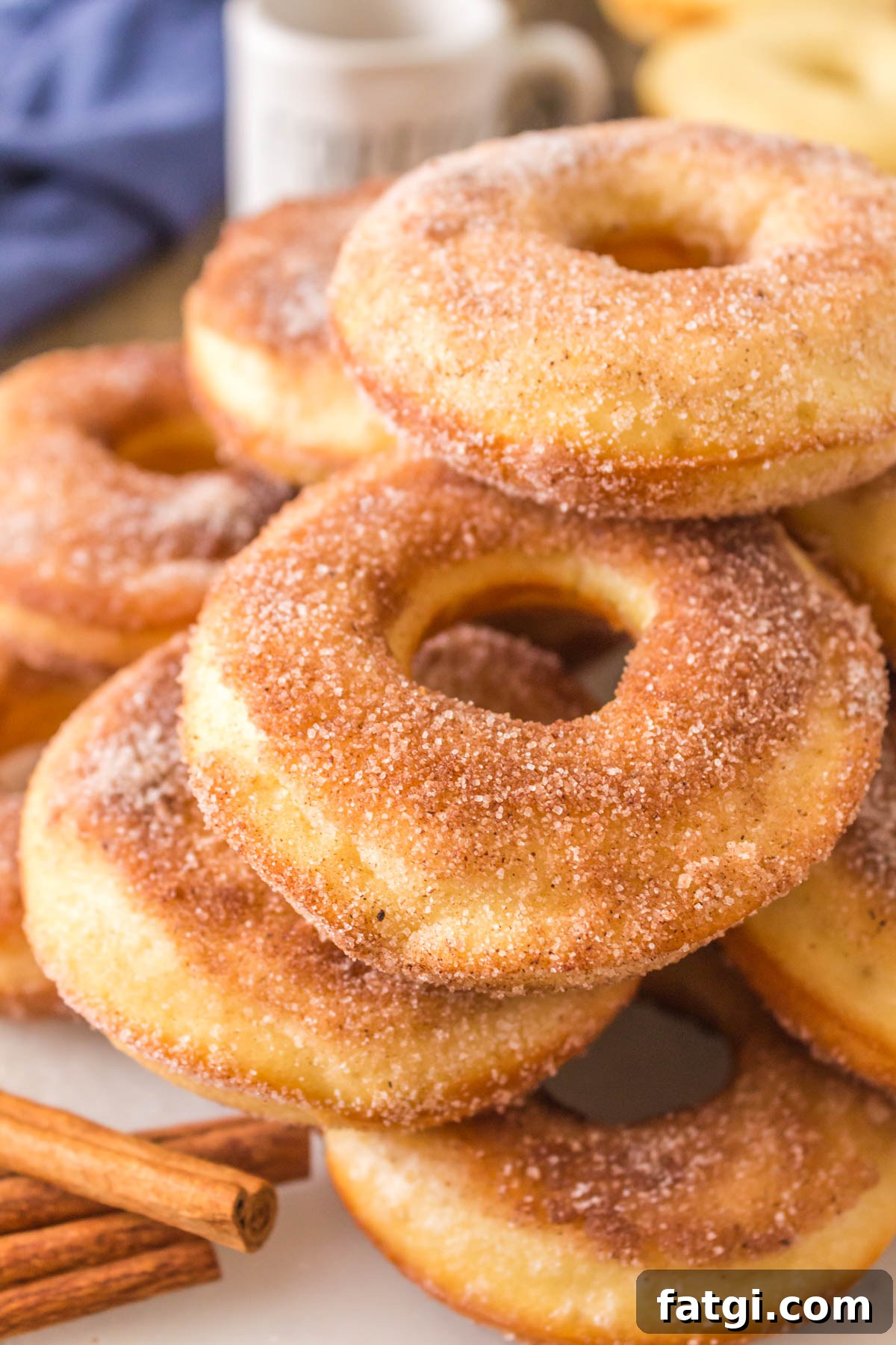 Stacked sourdough donuts on a plate, covered in cinnamon and sugar. 