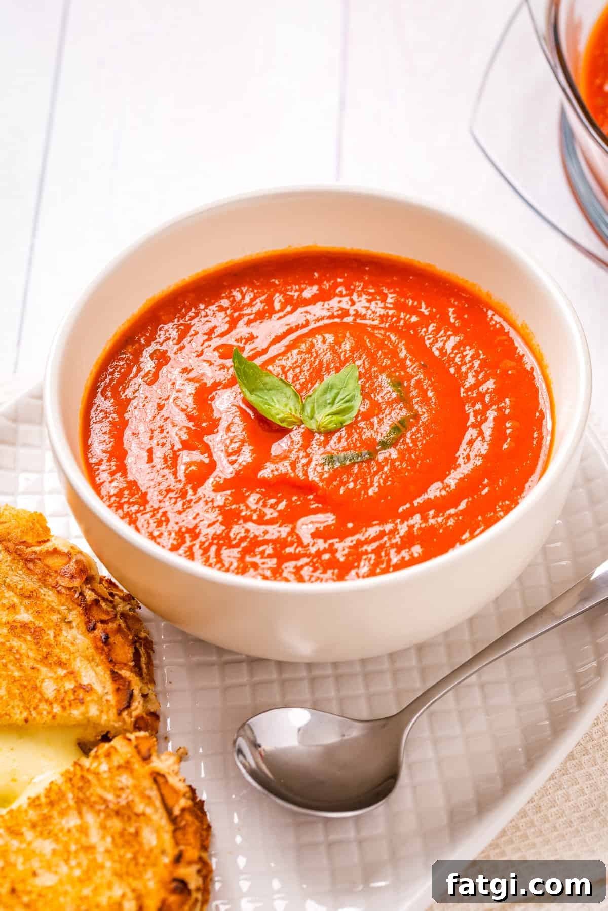 Instant Pot Tomato Soup with Fresh or Canned Tomatoes 2 Overhead view of instant pot tomato soup in a white bowl with cheese toasties on the side and a spoon.