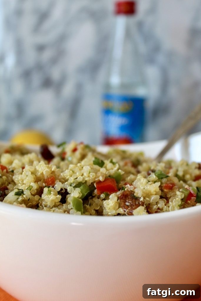 Refreshing Rose Water Quinoa Salad with Citrus & Feta 5 a close up of quinoa with bits of chopped red and green peppers and raisins