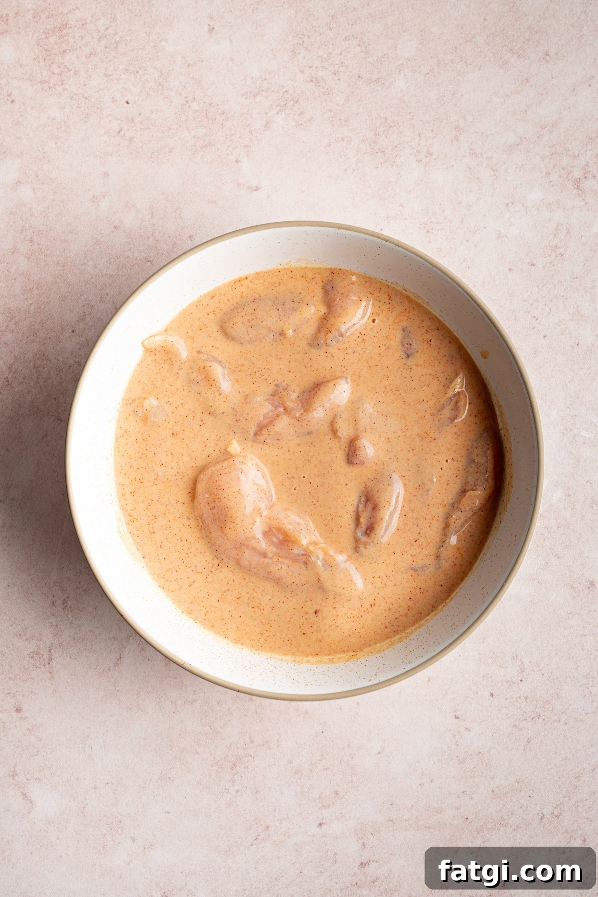 chicken tenders with buttermilk mixed into a bowl