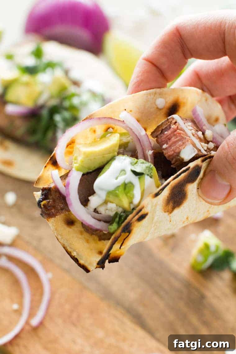 Steak Tacos topped with avocado, red onion and sour cream.