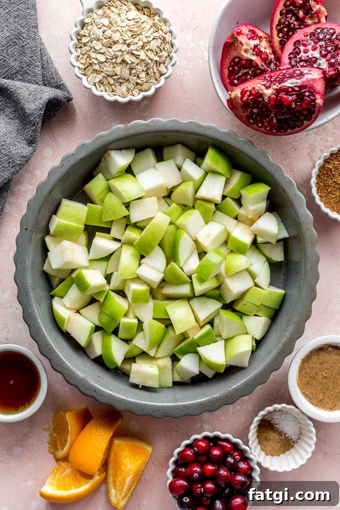 Ingredients to make apple cranberry crisp arranged individually on a pink surface.