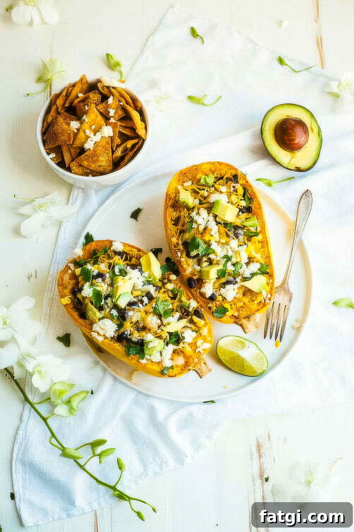 Mexican-Style Spaghetti Squash with Fresh Salsa 5 two mexican spaghetti squash on a white plate next to a halved avocado and a bowl of tortilla chips