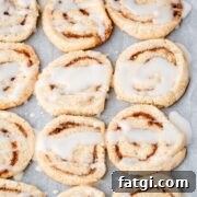 Glazed cinnamon roll cookies on parchment paper.