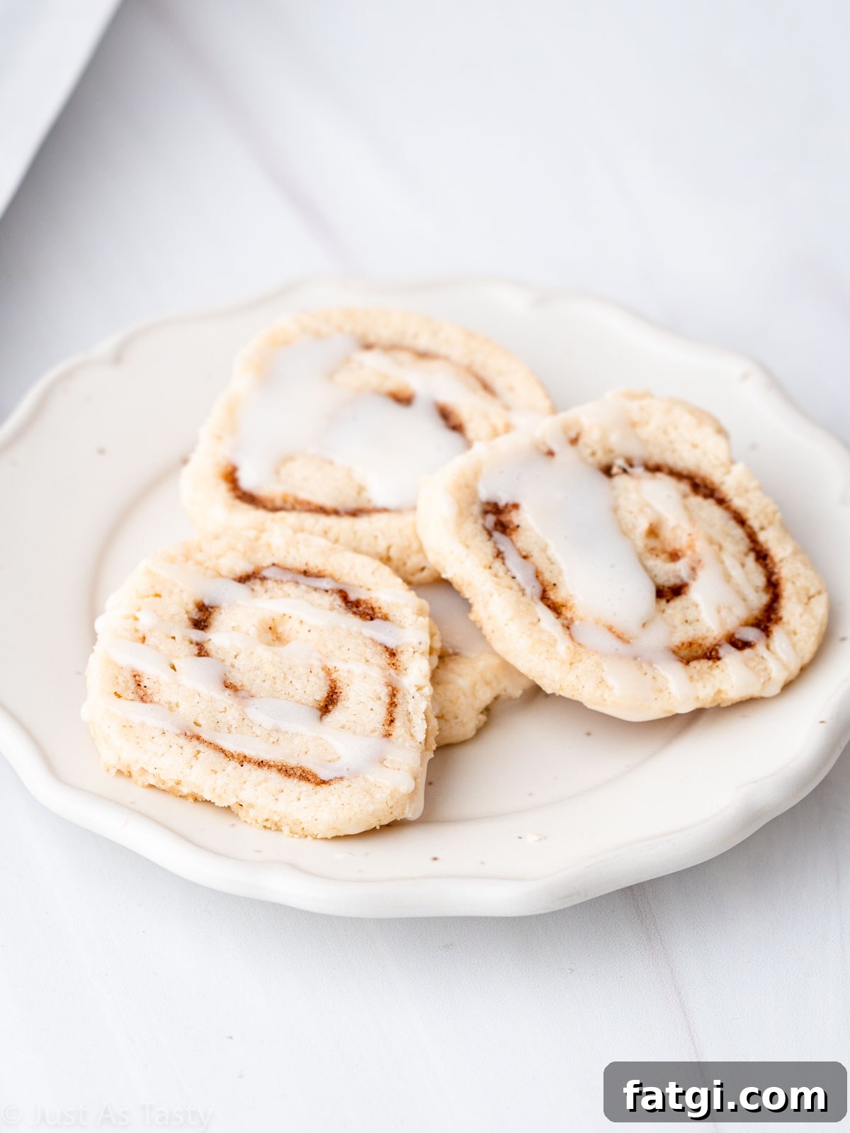 Glazed cinnamon roll cookies on a white plate.