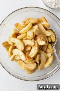 Homemade Gluten-Free Apple Crisp Recipe 6 Sliced apples tossed with spices in a glass bowl.