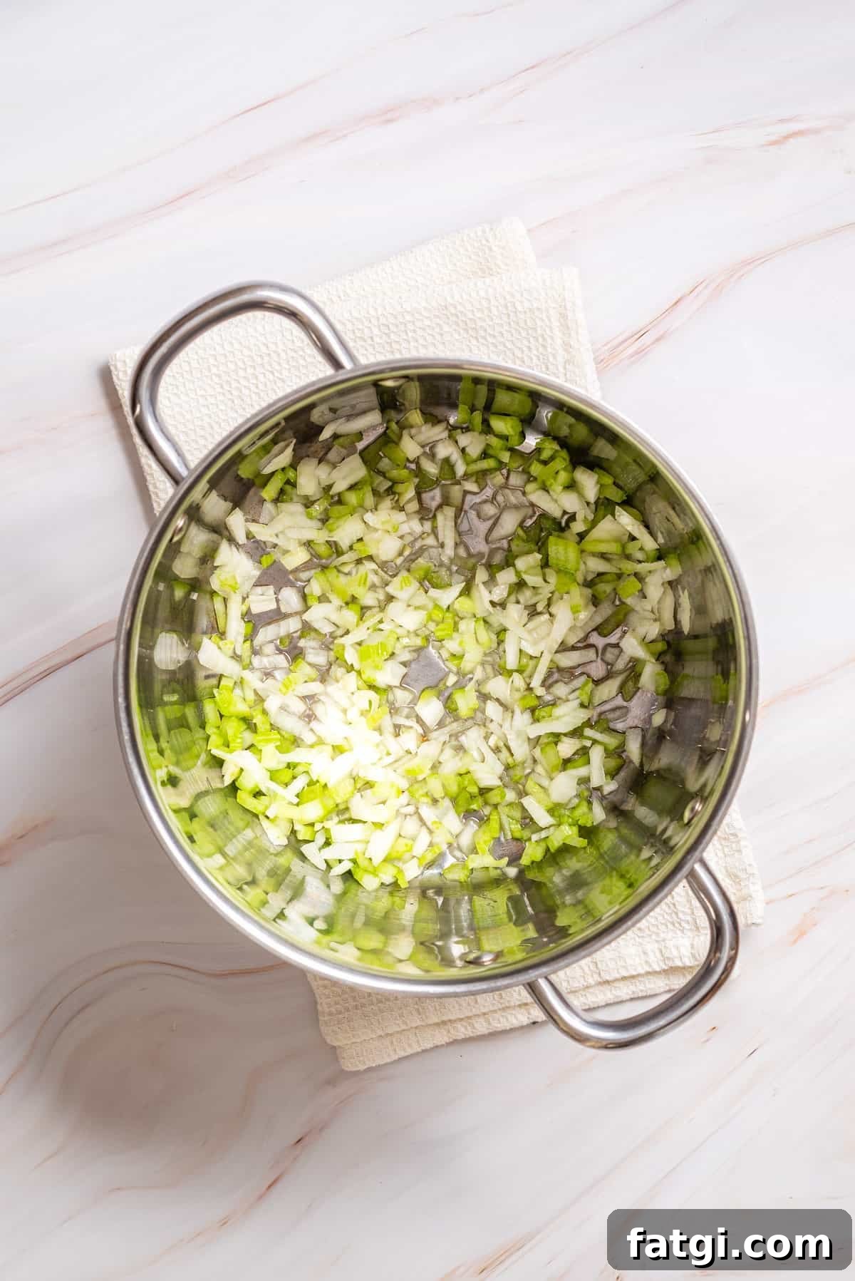 Overhead view of a pot with onions and celery.