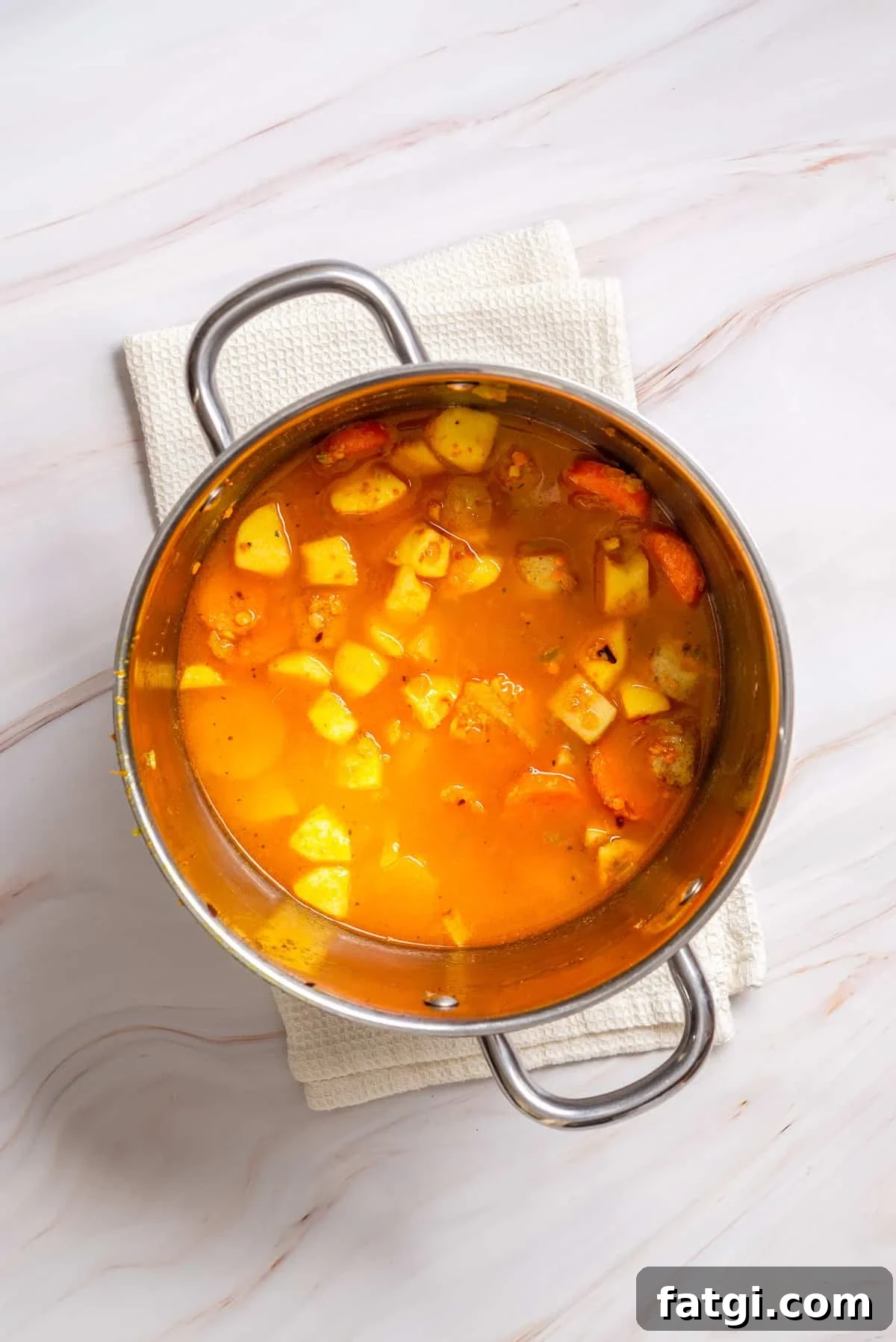 Overhead view of masoor dal and vegetable broth added to a pot.