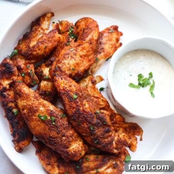 white bowl with blackened chicken tenders with a side of ranch topped with green onion.