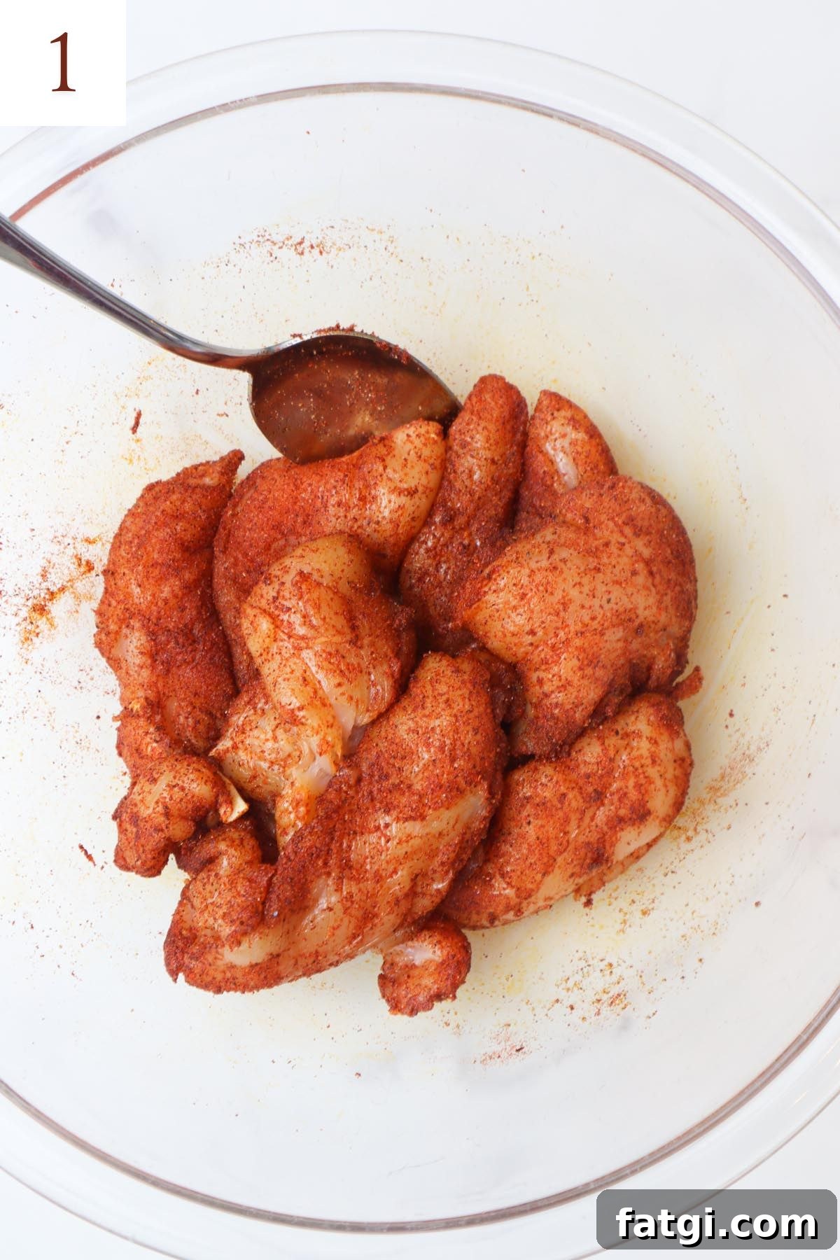 glass bowl with chicken tenders coated in oil and blackened seasoning.
