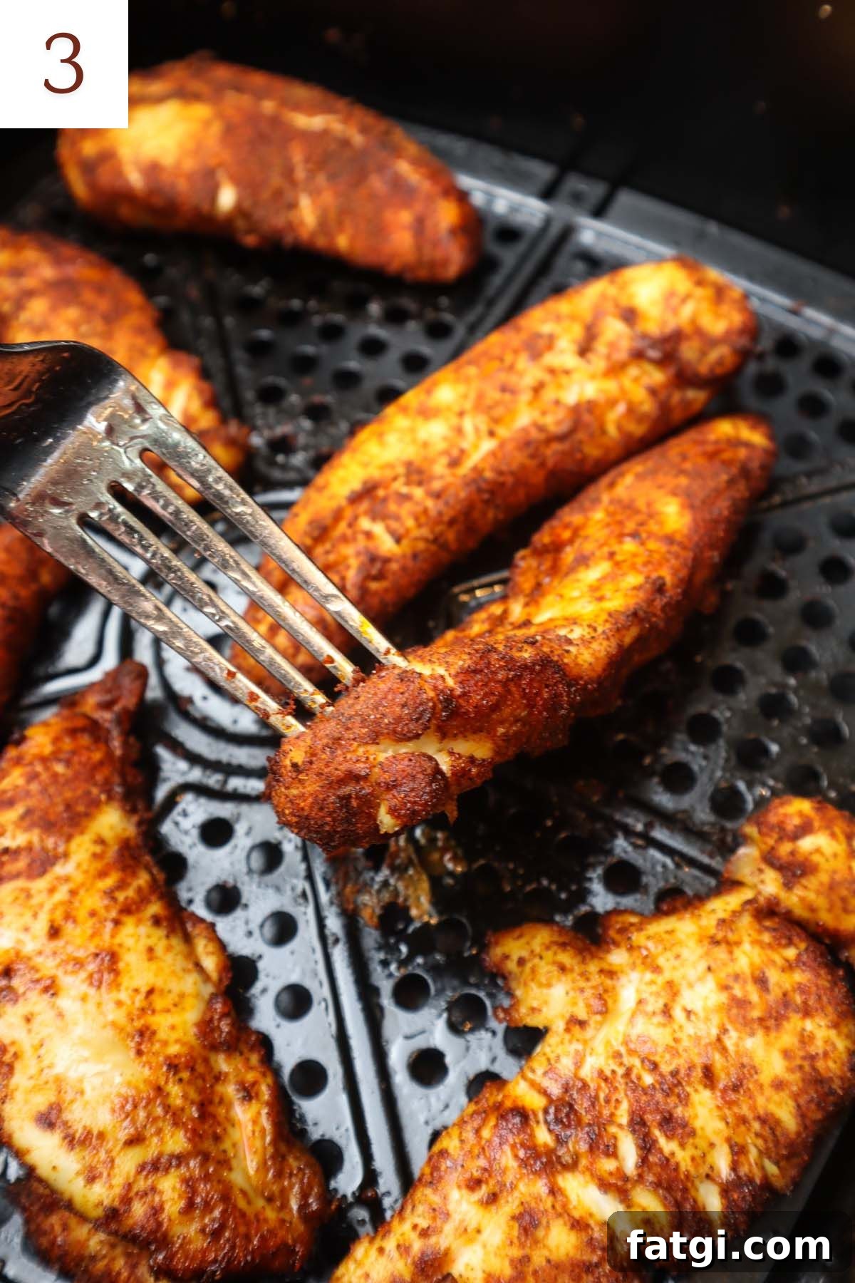 blackened chicken tenders in air fryer being flipped half way through cooking.